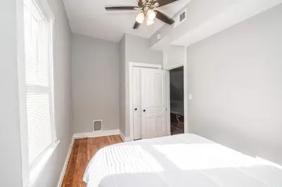 a white bedroom with a bed and a ceiling fan at Suites on Main 3 in Covington