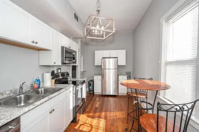 a kitchen with white cabinets and a table with chairs at Suites on Main 3 in Covington