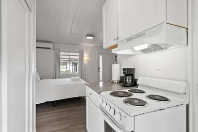 a white kitchen with a stove and a bed at Chic City Retreat 93I in Columbus