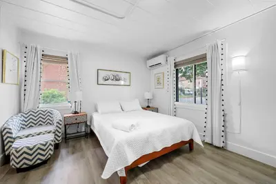 a white bedroom with a bed and a chair at Chic City Retreat 87 in Columbus