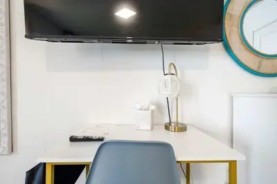a desk with a chair and a tv on a wall at Chic City Retreat 93A in Columbus