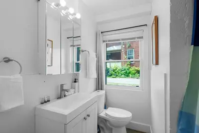 a white bathroom with a toilet and a window at Chic City Retreat 93A in Columbus