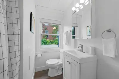 a white bathroom with a toilet and a window at Chic City Retreat 93B in Columbus
