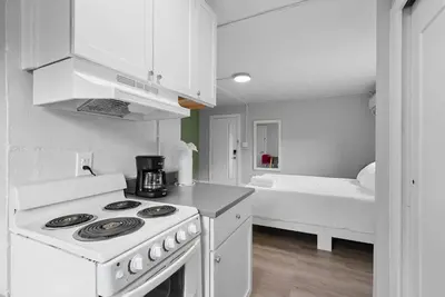 a white kitchen with a stove and a bed at Chic City Retreat 93D in Columbus