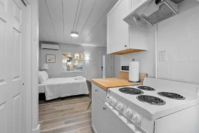 a white kitchen with a stove and a bedroom at Chic City Retreat 93E in Columbus