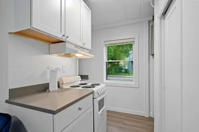 a white kitchen with a stove and a window at Chic City Retreat 93G in Columbus