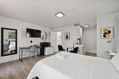 a bedroom with a white bed and a desk and a kitchen at Chic City Retreat 97 in Columbus
