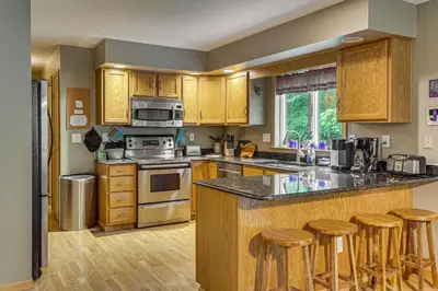 a kitchen with wooden cabinets and a island with bar stools at 2 Mi to Woodbury Wildlife Area Cozy Farmhouse! in Warsaw