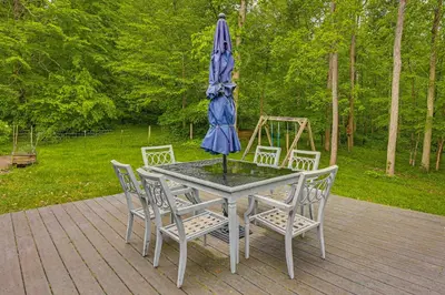 a table and chairs with an umbrella on a deck at 2 Mi to Woodbury Wildlife Area Cozy Farmhouse! in Warsaw