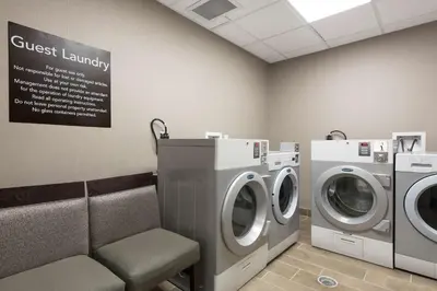 a laundry room with two washing machines and a chair at Homewood Suites by Hilton Cleveland/Sheffield in Avon