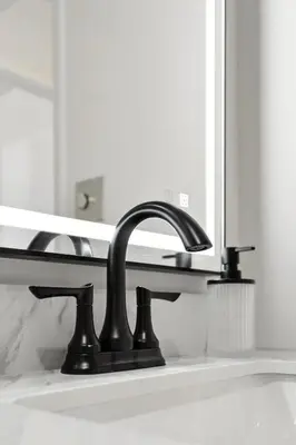 a bathroom sink with a black faucet in front of a mirror at The Mulberry in Logan