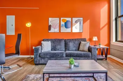 a living room with a couch and an orange wall at 1Br in Heart of Downtown, Sauna, Prime Location in Cleveland