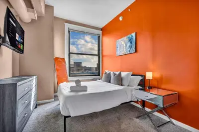 a bedroom with an orange wall with a bed and a television at 1Br in Heart of Downtown, Sauna, Prime Location in Cleveland
