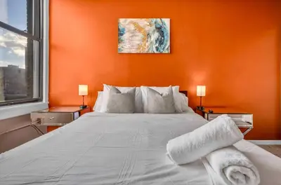 a bedroom with a large white bed with an orange wall at 1Br in Heart of Downtown, Sauna, Prime Location in Cleveland