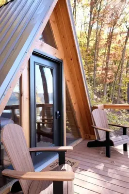a cabin with two chairs and a door on a deck at Secluded A-Frame Incredible for Water Activities by Tappan Lake in Ohio in Deersville