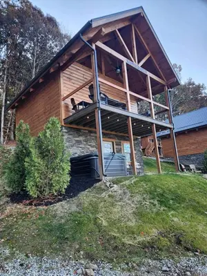a house with a dog sitting on a balcony at Group Friendly Cabin with Spa on the Deck near Tappan Lake in Ohio in Deersville