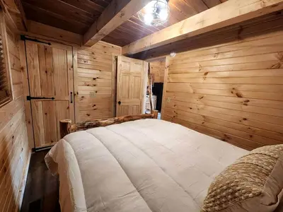 a bedroom with a large bed in a room with wooden walls at Lakeview Cabin by Tappan Lake, Perfect for Groups with Hot-Tub in Ohio in Deersville