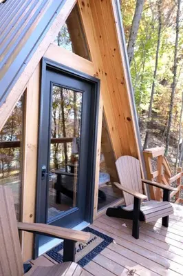 a cabin with a glass door and two chairs on a deck at Two Person A-frame near Tappan Lake, Ideal to Reconnect with Nature in Ohio in Deersville