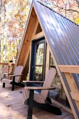 two chairs and a table on a porch of a cabin at Two Person A-frame near Tappan Lake, Ideal to Reconnect with Nature in Ohio in Deersville