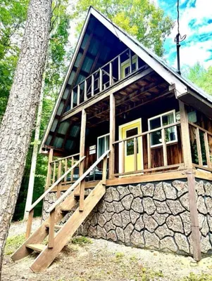 a cabin in the woods with a stone wall at Gorgeous Secluded Cabin with Hiking Trails Near in Frenchburg, Kentucky in Frenchburg