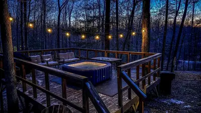 a deck with a hot tub in the woods at night at Gorgeous Secluded Cabin with Hiking Trails Near in Frenchburg, Kentucky in Frenchburg