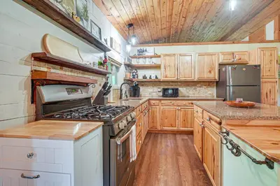 a kitchen with wooden cabinets and a stove top oven at Pond and Fire Pit Charming Log Cabin near Blue Rock in Blue Rock