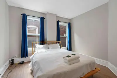 a bedroom with a large bed with blue curtains at Merion Village Residences - Peaceful Columbus Neighborhood in Columbus