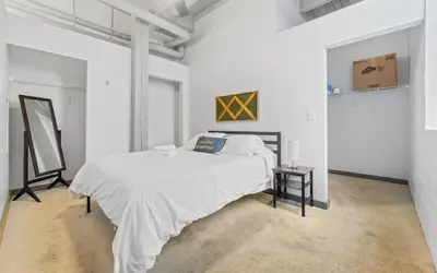 a white bedroom with a bed and a table at Downtown Loft l Cleveland l Parking l Cafe in Cleveland