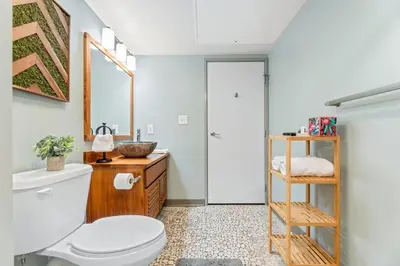 a bathroom with a white toilet and a wooden cabinet at Downtown Loft l Cleveland l Parking l Cafe in Cleveland