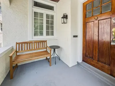 a wooden bench sitting on a porch next to a door at Cozy Urban Farmhouse 3bd1andhalfbth in Cincinnati