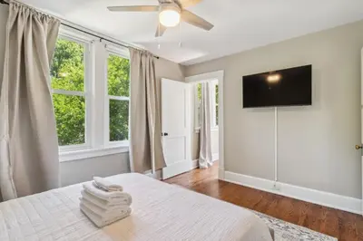 a bedroom with a bed with a ceiling fan and windows at Cozy Urban Farmhouse 3bd1andhalfbth in Cincinnati