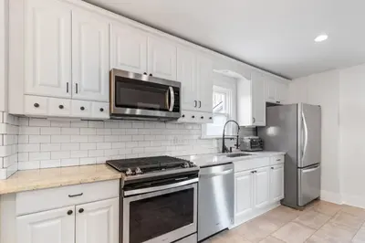 a kitchen with white cabinets and a stainless steel refrigerator at HydePark Abode Two 1st flr bedrms in Cincinnati