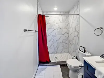 a bathroom with a shower with a red shower curtain at WalnutHills Mansion-sleeps14! TVs in every room! in Cincinnati