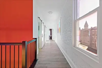 an empty hallway with orange and white walls and windows at WalnutHills Mansion-sleeps14! TVs in every room! in Cincinnati