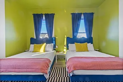 two beds in a room with two windows at WalnutHills Mansion-sleeps14! TVs in every room! in Cincinnati