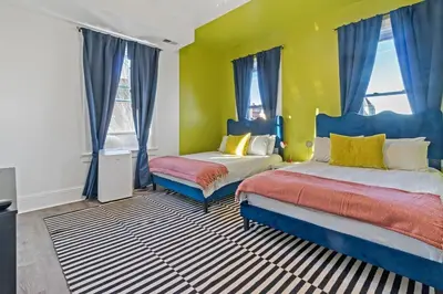 a bedroom with two beds and a yellow wall at WalnutHills Mansion-sleeps14! TVs in every room! in Cincinnati
