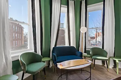 a waiting room with chairs and a table and windows at WalnutHills Mansion-sleeps14! TVs in every room! in Cincinnati
