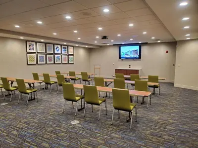 a conference room with tables and chairs and a screen at Holiday Inn Express & Suites Sandusky by IHG in Sandusky