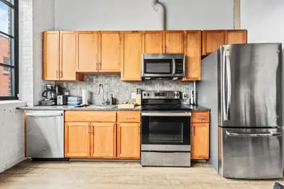 a kitchen with wooden cabinets and a stainless steel refrigerator at Studio Apt In DT l Parking l Fast Wi-fi l Café in Cleveland