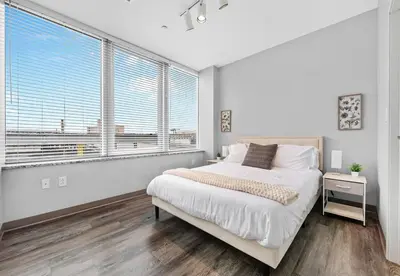 a white bedroom with a bed and large windows at Near DT & CLE Clinic Queen Bed Wi-Fi Parking in Cleveland