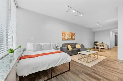 a bedroom with a large bed and a living room at MDRN Escape with Natural Light Wi-Fi Gym Parking in Cleveland