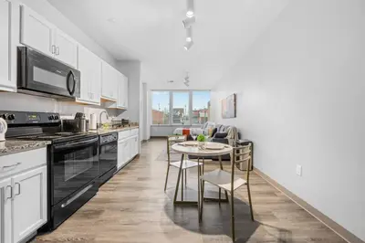 a kitchen with white cabinets and a table with chairs at MDRN Escape with Natural Light Wi-Fi Gym Parking in Cleveland