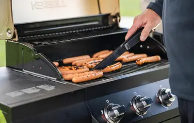 a man is cooking hot dogs on a grill at My Place Hotel-Pittsburgh North/Monaca, PA in Monaca