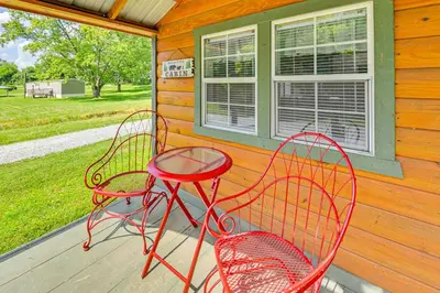 a porch with two red chairs and a table at 14 Mi to Kentucky Horse Park Creekside Cabin in Georgetown