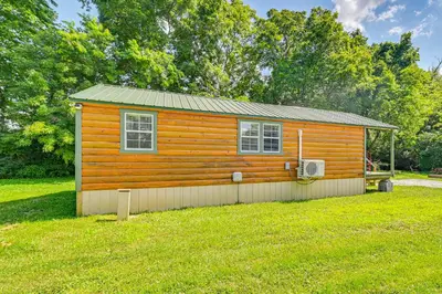 a small wooden cabin in a field of grass at 14 Mi to Kentucky Horse Park Creekside Cabin in Georgetown