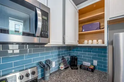 a kitchen with a microwave and blue tiles at OTR 2 Lux Queen Beds Sleeps 5ppl Light Rail Wifi in Cincinnati
