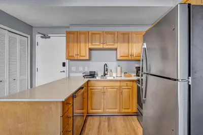 a kitchen with wooden cabinets and a stainless steel refrigerator at 1BR Loft Sauna & Walk to Theater & Campus in Cleveland