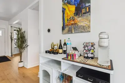 a white kitchen with a counter with bottles of wine at Luxury Olivewood Oasis - 13 mins to Cleveland in Lakewood