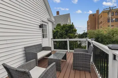 a balcony with wicker chairs and a bench at Luxury Olivewood Oasis - 13 mins to Cleveland in Lakewood
