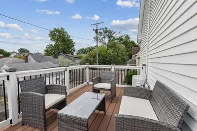 a balcony with wicker chairs and a wooden table at Luxury Olivewood Oasis - 13 mins to Cleveland in Lakewood